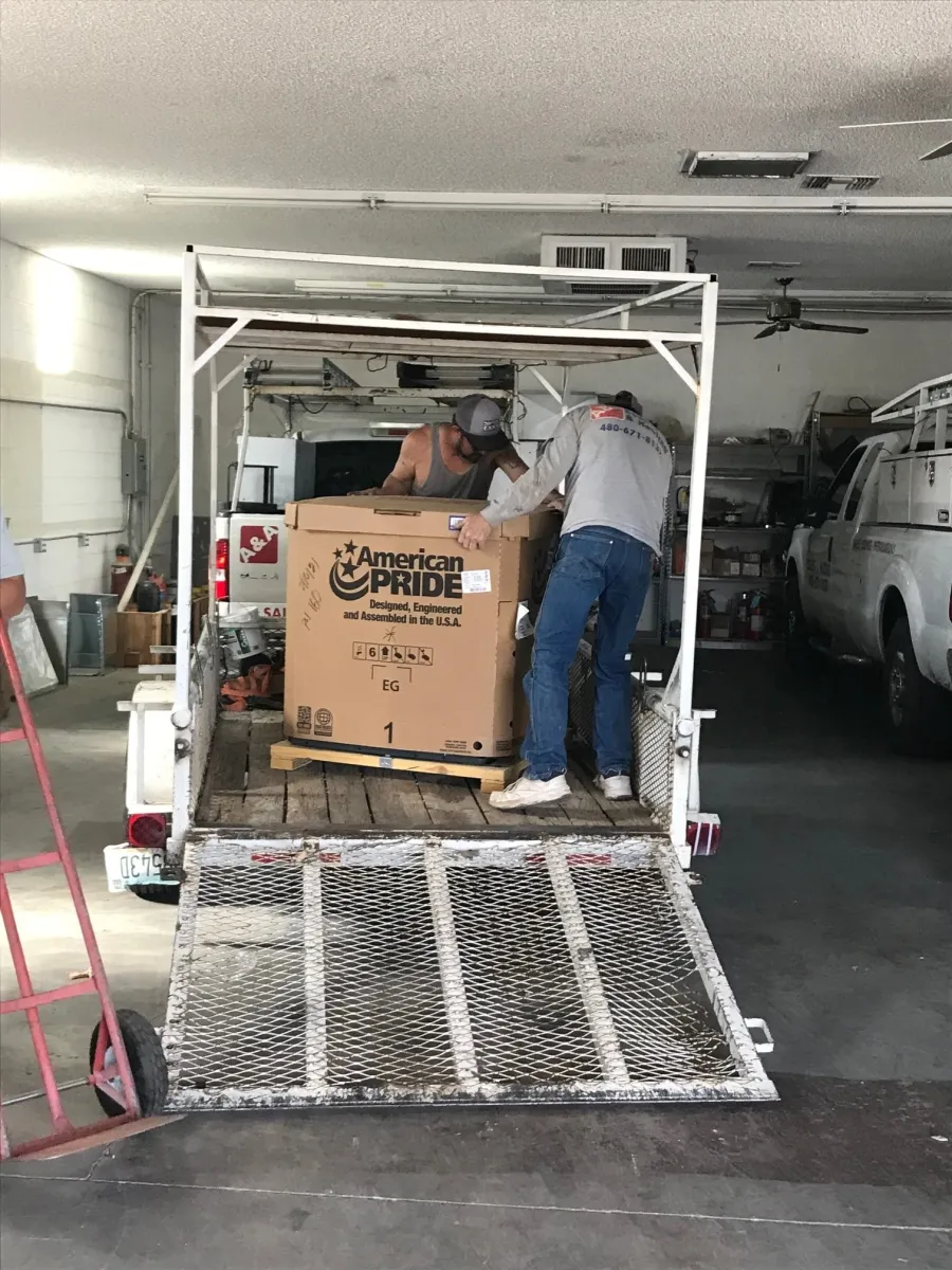 A&A Cooling & Heating techs loading a new system onto the shop trailer